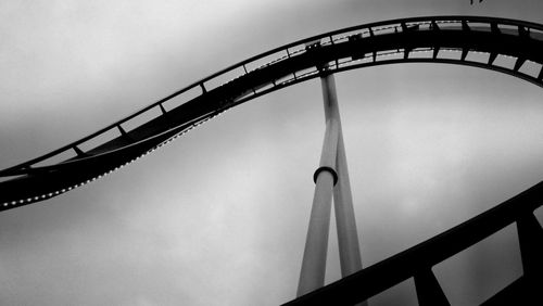 Low angle view of rollercoaster ride against sky at dusk