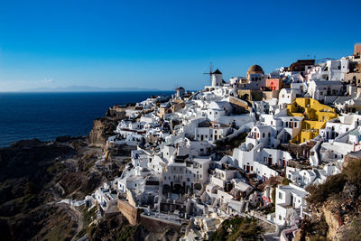 Townscape by sea against clear blue sky