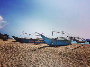 Outrigger boats moored at beach against sky