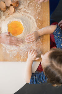 Children preparing dough while standing together at kitchen table with flour