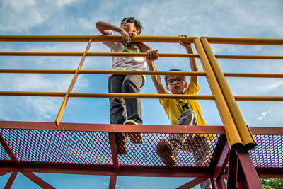 Low angle view of kids at playground against sky