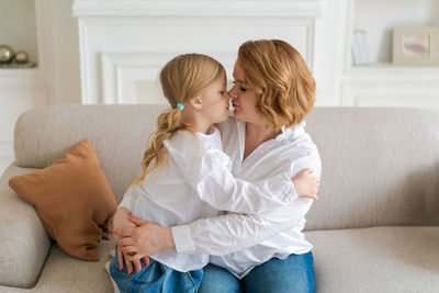 Close-up cropped image smiling little daughter hugging caucasian mom, family