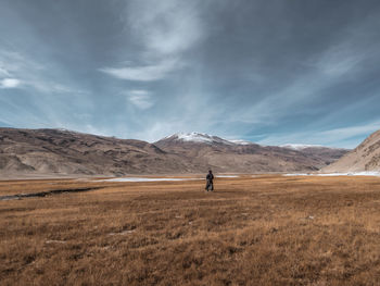 Man walking on field against sky