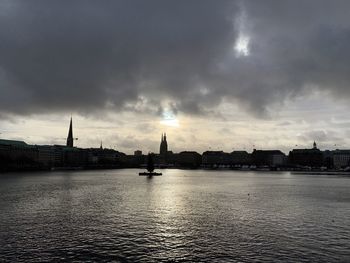 View of buildings by river against cloudy sky