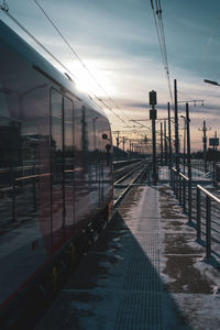 Train at railroad station against sky during sunset