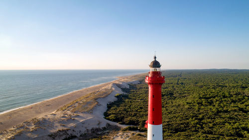 Lighthouse by sea against sky