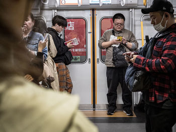 People standing by train in city