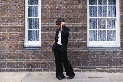 Young man wearing sunglasses standing on footpath