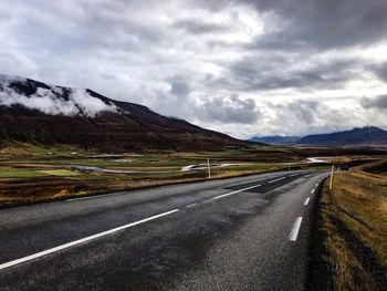 Road leading towards mountains against sky