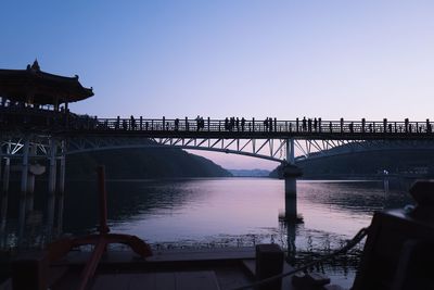 Silhouette of bridge over river against clear sky