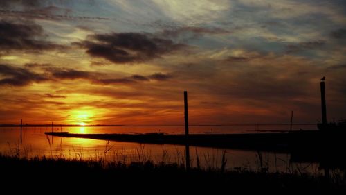 Scenic view of lake against dramatic sky during sunset