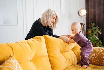 Side view of woman using mobile phone while lying on bed at home
