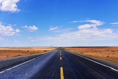 Road passing through land against sky