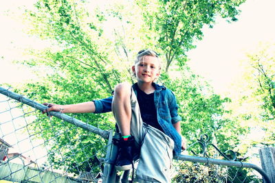 Portrait of smiling boy on bicycle against trees