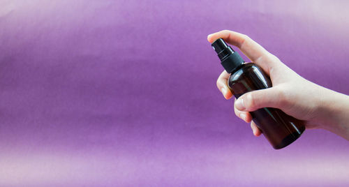 Close-up of woman hand holding purple bottle