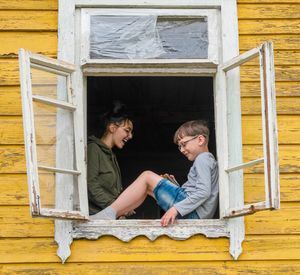 Portrait of two siblings at home near opened window