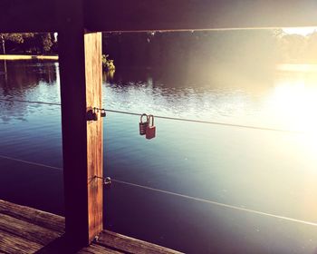 Reflection of railing in lake against sky during sunset