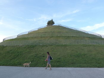 Side view of woman with dog walking on road at park