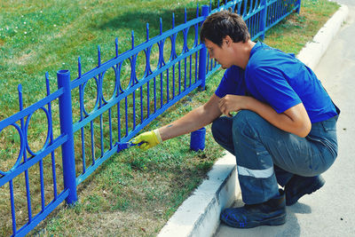 Side view of boy on fence against plants