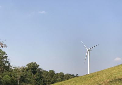 Low angle view of wind turbines on field against sky