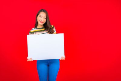 Portrait of a smiling young woman against red background