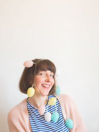 Portrait of smiling young woman with multi colored lighting equipment over white background