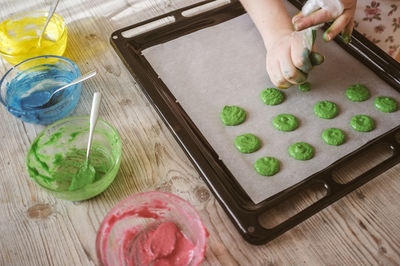 Cropped image of hand making cookies in baking sheet