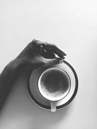 Close-up of hand holding coffee cup against white background