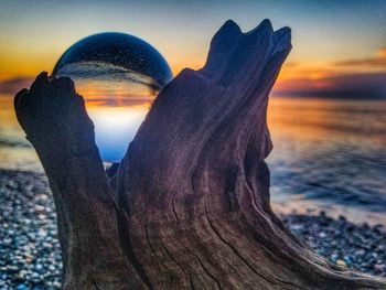 Close-up of human hand against sky during sunset