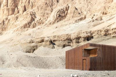 Modern wooden house surrounded by desertic landscape of white and yellow sand in north africa