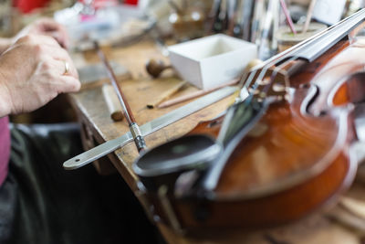 Cropped hands of woman by violin at table