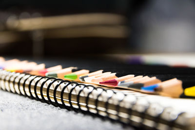 Close-up of multi colored pencils with note pad on table