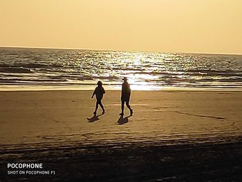 Silhouette man on beach against sky during sunset