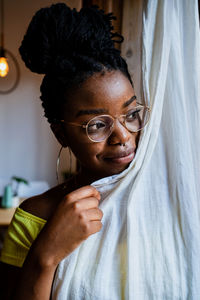 Portrait of young woman holding eyeglasses at home