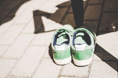 Low section of person wearing shoes on footpath