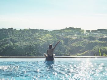 Young man in swimming pool against sea