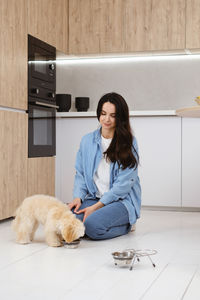 Portrait of young woman with dog on floor at home