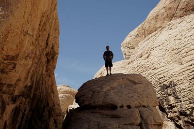 Low angle view of man standing on cliff against clear sky