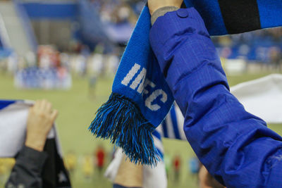 Cropped hand holding purple scarf at stadium