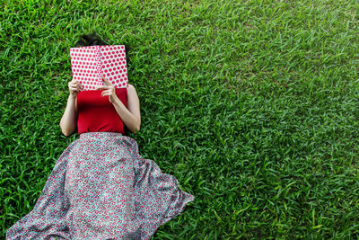 High angle view of young woman relaxing on field