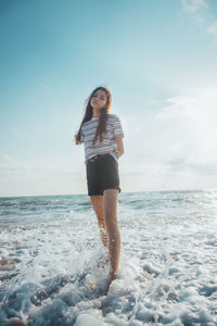 Full length of young woman at beach against sky