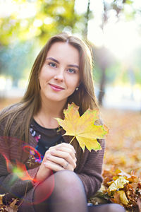 Portrait of a smiling young woman holding autumn leaves