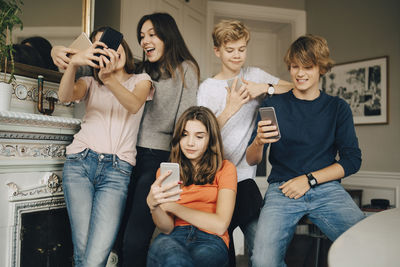 Cheerful friends using smart phones in living room