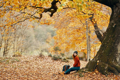 Woman sitting on sidewalk during autumn