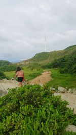 Rear view of woman working on field against sky