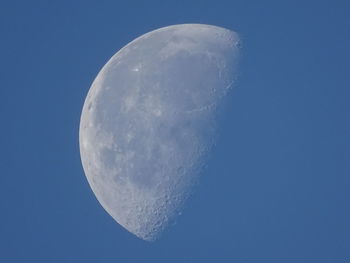 Low angle view of half moon against clear blue sky