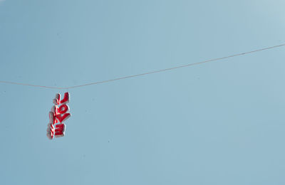 Low angle view of flags hanging against clear blue sky