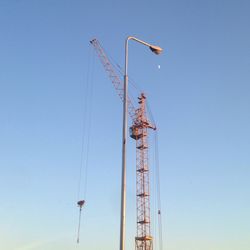 Low angle view of crane against clear blue sky