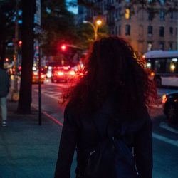 Rear view of woman walking on road in city at night
