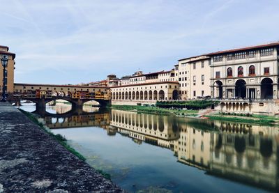 Arch bridge over river against buildings in city